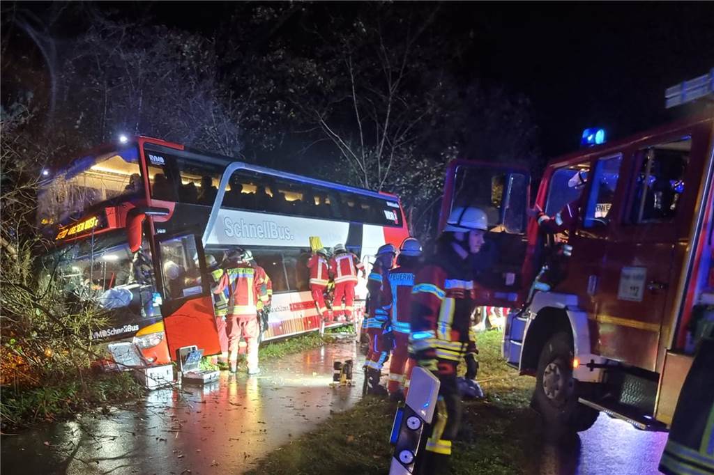 Feuerwehrleute kümmern sich um Fahrgäste und sichern den Doppeldeckerbus.