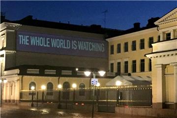 Der Schriftzug „The Whole World is Watching“ wird an eine Wand am Präsidentenpalast in Helsinki projiziert. Foto: Maren Hennemuth