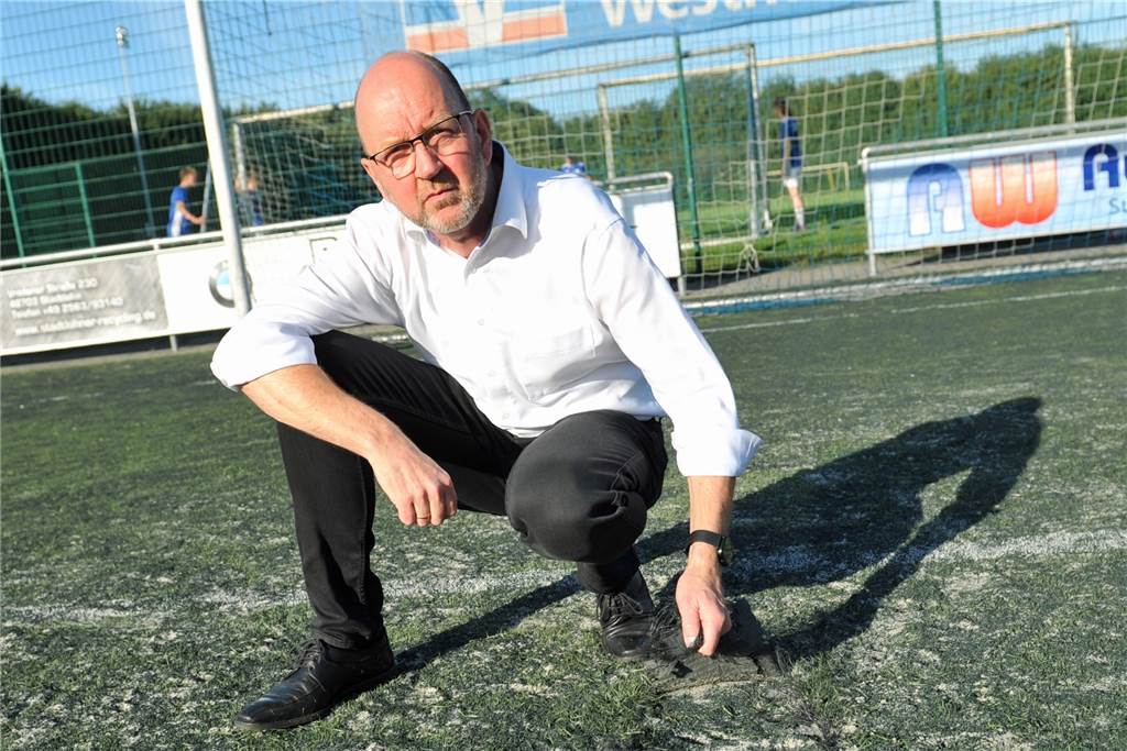 Neue Umkleide für den SuS: „Der Druck auf dem Kessel ist erhöht worden“ Der SuS-Vorsitzende Wilfried Steinhage hält ein Stück des ramponierten Kunstrasens in der Hand. Das Loch vor ihm ich etwa 20 mal 20 Zentimeter groß und stellt für Fußballer ein Verletzungsrisiko dar.