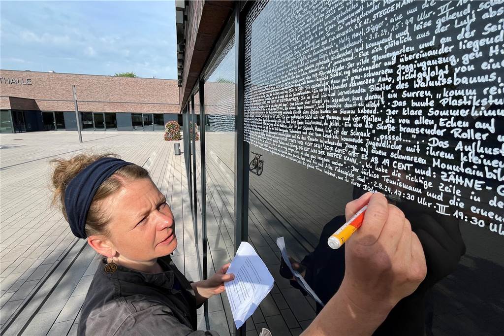 Vera Vorneweg schreibt Handschrift auf die Fassade der Stadtbibliothek Vera Vorneweg schreibt auf die Fenster der Stadtbibliothek