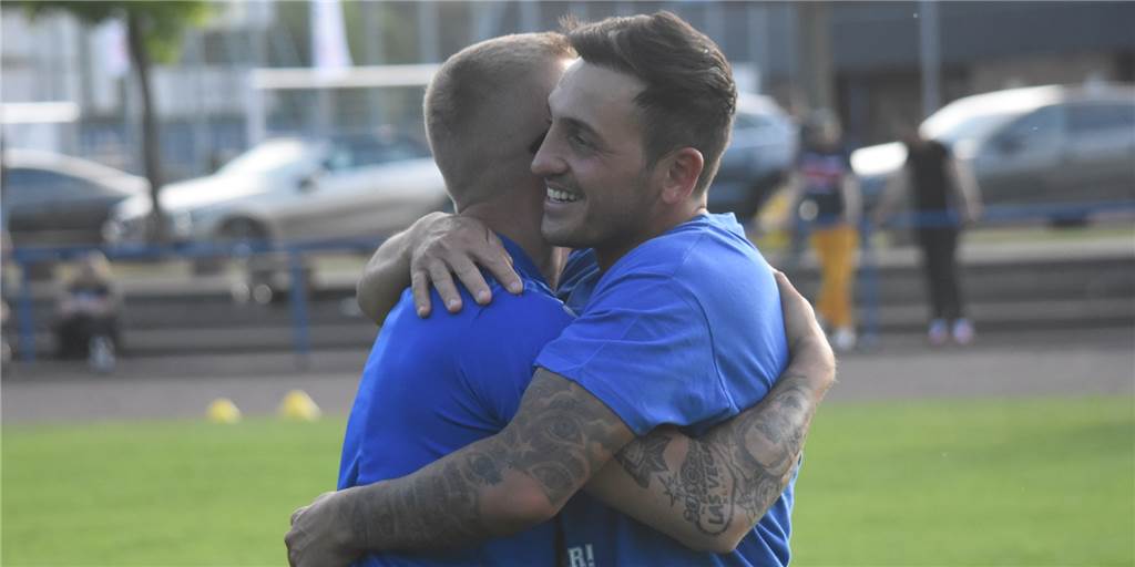 VfL Kamen feiert: 6 Videos vom Bezirksliga-Aufstieg – „Mit Bier können wir uns die Zähne putzen! Der verletzte Björn Scharfe (l.) umarmt Doppeltorschützen Murat Büyükdere herzlich.