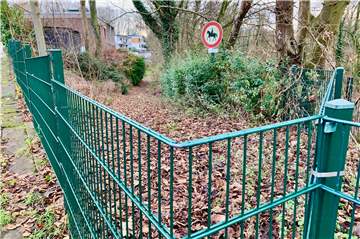 Der Weg aus Blickrichtung Norden: Ein Zaun versperrt den Durchgang. Im Hintergrund ist noch das Schild „Reiten verboten“ zu sehen.