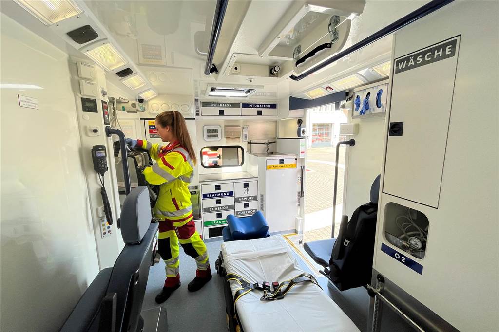 Alyssa Brauckmann ist Notfallsanitäterin: „Das ist hier ein tolles Team“ Alyssa Brauckmann steht im Rettungswagen, den man im Weitwinkel sieht. In der Mitte steht eine Liege, an den Wänden hängen überall Gerätschaften und Schränke mit Material.
