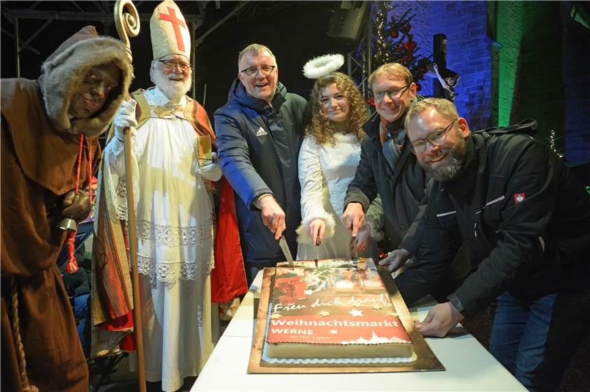 Der Werner Weihnachtsmarkt auf dem Kirchhof ist am Freitag, 6. Dezember, gestartet. Bürgermeister Lothar Christ (2.v.r.) schnitt gemeinsam mit David Ruschenbaum (r.) und Pfarrdechant Jürgen Schäfer die Baumkuchentorte an - und verteilte sie dann mit Unterstützung von Nikolaus, Engel und Knecht Ruprecht unter den Besuchern.