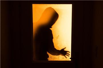 Der Schatten eines Mannes ist hinter einer gläsernen Wohnungstür zu sehen. Foto: Nicolas Armer/Archiv