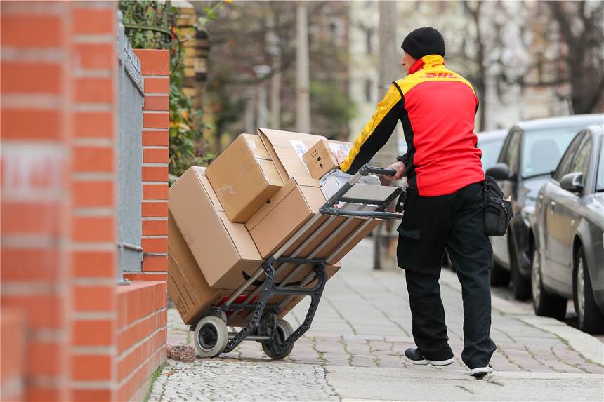 CDU will Pakete beim Online-Kauf teurer machen – zum Wohl der Innenstädte DHL-Paketzusteller mit voll beladenem Karren beim Ausliefern von Paketen.