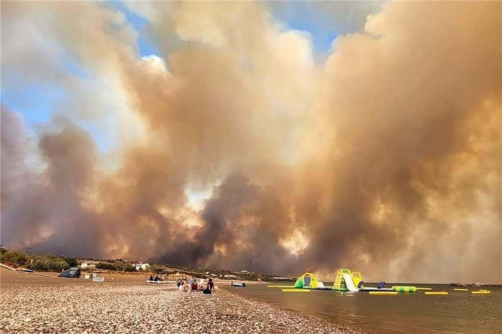 Nach Rhodos trotz Bränden: „Die Gefühlslage ist gemischt“ Dichte Rauchwolken eines Waldbrandes verdunkeln auf der griechischen Insel Rhodos den Himmel über den Stränden im Südosten der Insel. Während hier mehrere Orte evakuiert werden, können Touristen in anderen Regionen weiter auf Rhodos Urlaub machen.