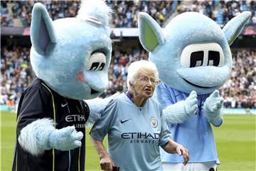Die 102 Jahre alte Vera Cohen wird von den beiden Maskottchen Moonchester (r) und Moonbeam nach dem Einlaufen vom Spielfeld geleitet. Foto: Martin Rickett/PA Wire