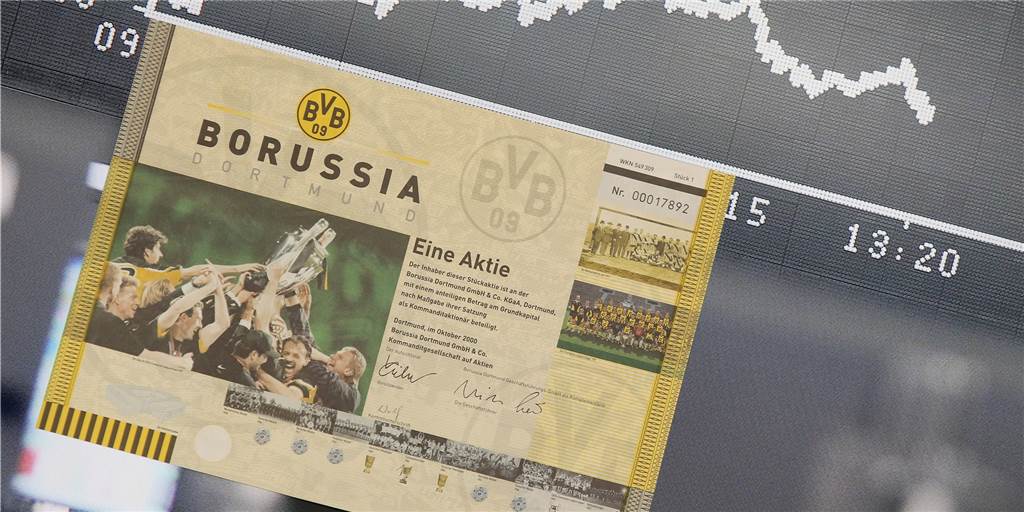 Absturz: BVB-Aktie fällt so tief wie seit fast zehn Jahren nicht Eine Aktie von Borussia Dortmund vor einem Bildschirm mit dem Kursverlauf.