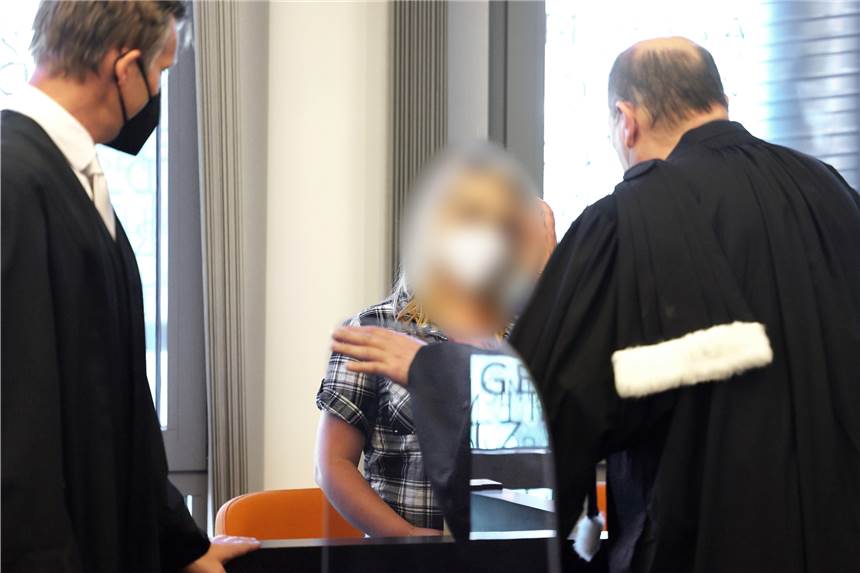 Prozess um Mord an fünf Kindern: Verteidiger kritisieren Gutachter scharf Die angeklagte Mutter (M) steht zwischen ihren Anwälten im Gerichtssaal.