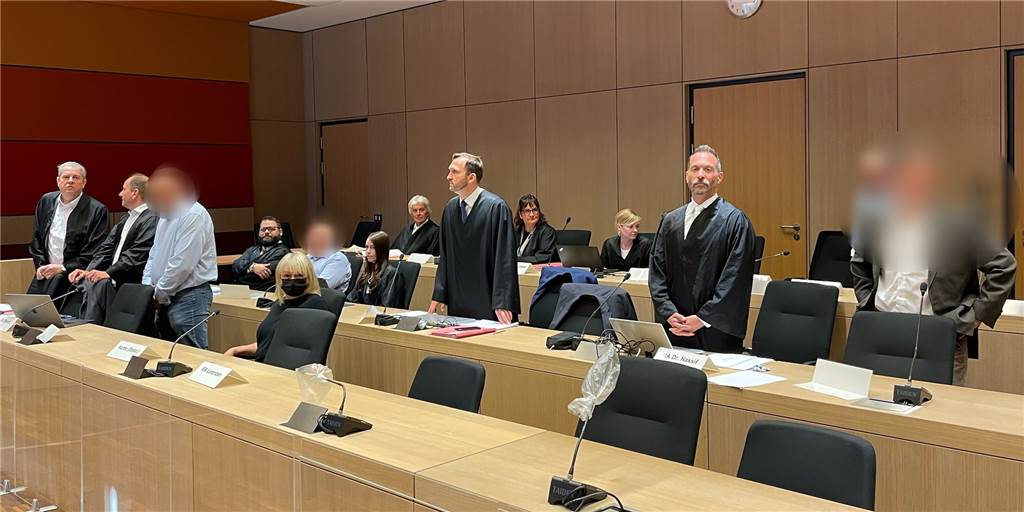 Die Angeklagten an der Seite ihrer Verteidiger und Dolmetscher kurz vor Prozessbeginn. Ganz rechts außen: der angeklagte Rechtsanwalt. In der zweiten Reihe, zweiter von links (noch sitzend): der Kfz-Gutachter.