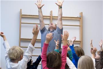 Die Arme in die Luft, sich groß machen und stark fühlen: Persönlichkeitstrainer Jürgen Rüstow zeigt den Kindern in der Berliner Kindertagesstätte „Wolkenzwerge“ eine Übung. Foto: Alexander Heinl/dpa-tmn