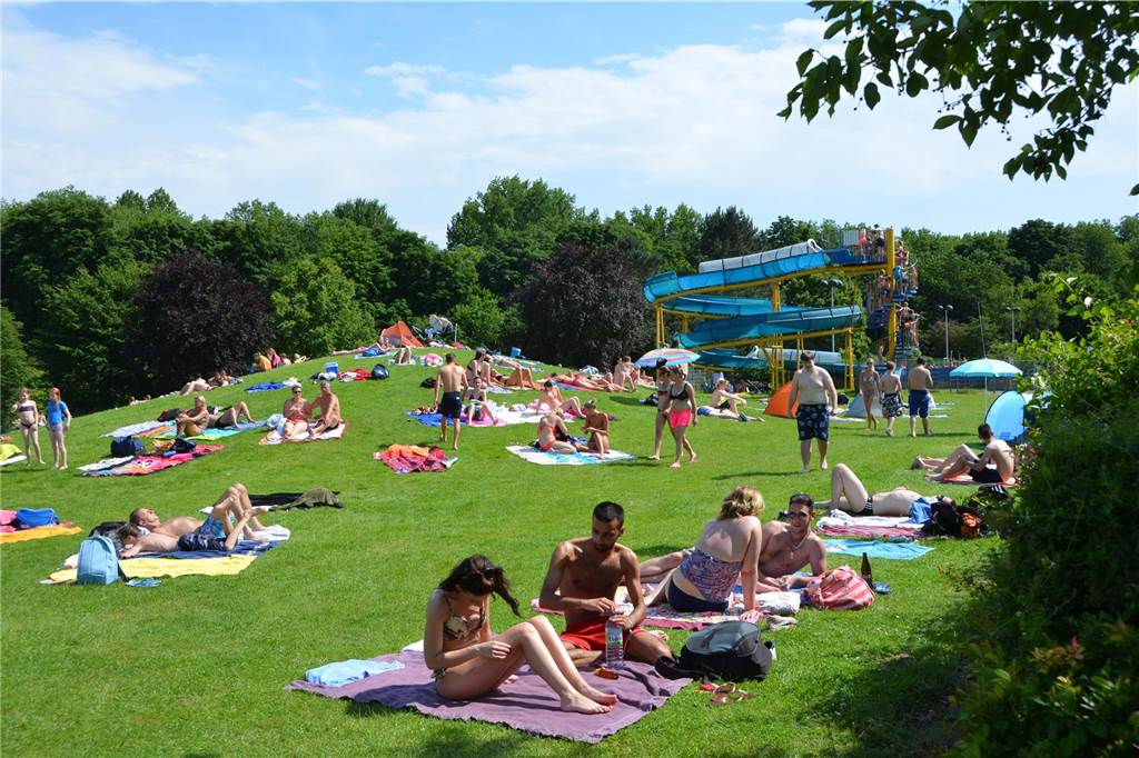 Für die Eröffnung der Badesaison muss nur noch das Wetter stimmen Badegäste liegen auf Handtüchern auf der Wiese im Freibad Aquarell.