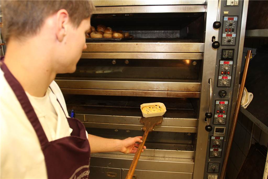 Ein Azubi der Bäckerei Telgmann in Werne schiebt einen Stollen in den Ofen.