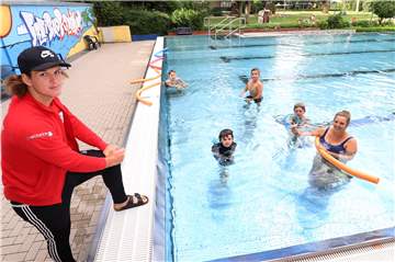Die beiden Übungsleiter Emmanuel Drote (stehend) und Isabella Drote (im Wasser) üben mit den Kindern im Freibad Bornekamp das Tauchen nach einem Ring.