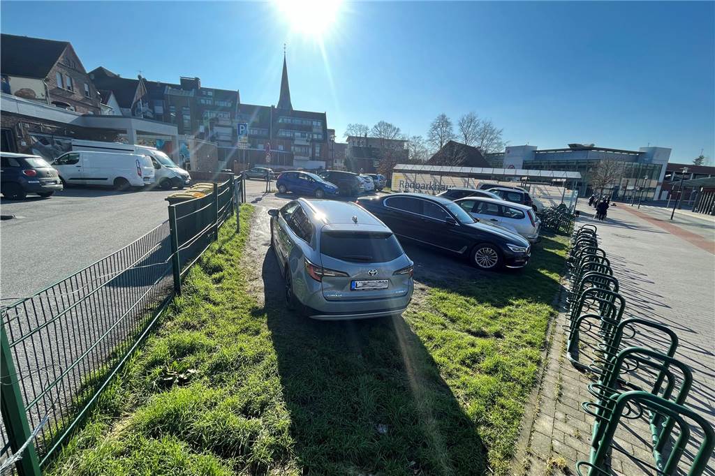 Autos stehen auf dem Parkplatz am Grundstücksrand.