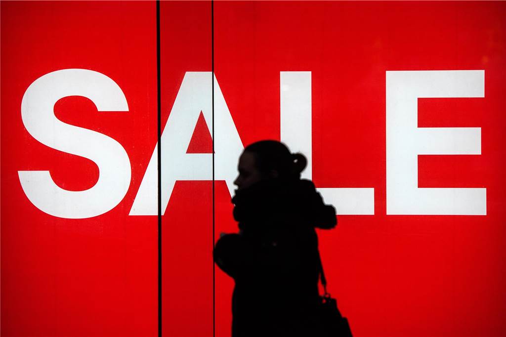 Tipps zum Black Friday 2024: Wie kann man am besten sparen und was sind die Gefahren? Eine Frau geht in der Innenstadt an einem Schaufenster mit einem Schild SALE entlang