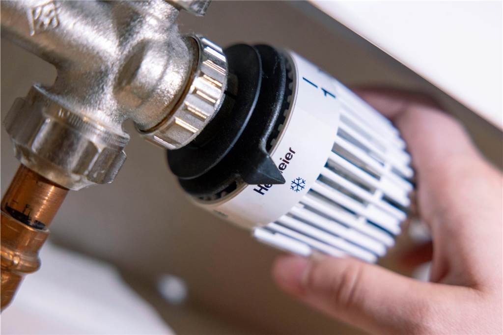 Eigenheim im Sinne des Heizungsgesetzes fit machen: Darauf sollten Sie achten Eine Person dreht am Thermostat einer Heizung.