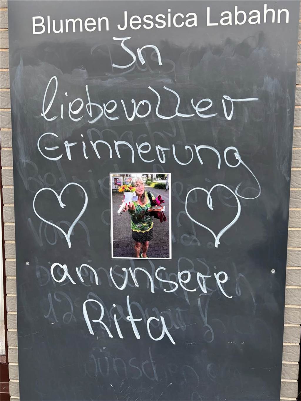 „Däumchen drücken, Jamaika ruft!“: So erinnert sich Hillen an die getötete Rita (71) Auf einer schwarzen Tafel (Blumen Jessica Labahn in Recklinghausen) steht mit weißer Kreide "In liebevoller Erinnerung an unsere Rita"