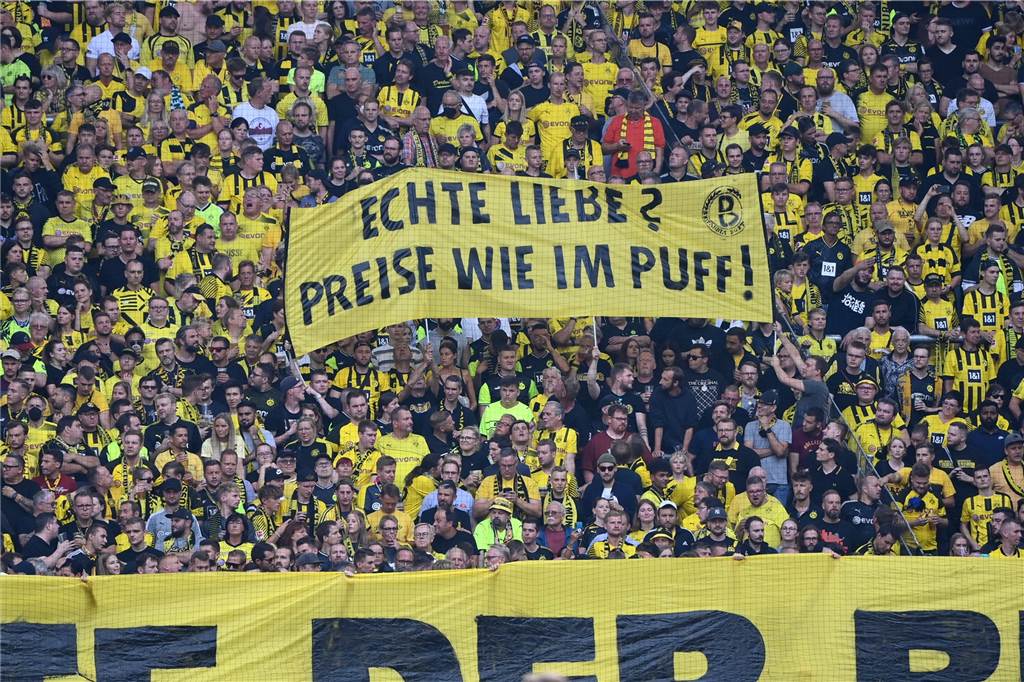 Nach Fan-Protesten gegen Ticketpreise: So reagiert der BVB BVB-Fans halten ein Banner hoch mit der Aufschrift: "Echte Liebe? Preise wie im Puff!"