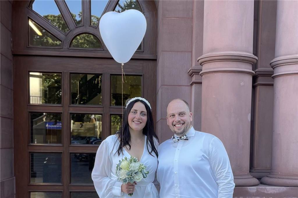 Er verkleidete sich für den Antrag: Jan und Anastasia haben geheiratet Die Braut trägt einen weißen Herzluftballon um ihr Handgelenk. Er schwebt in der Höhe. Neben ihr steht ihr Bräutigam Jan.