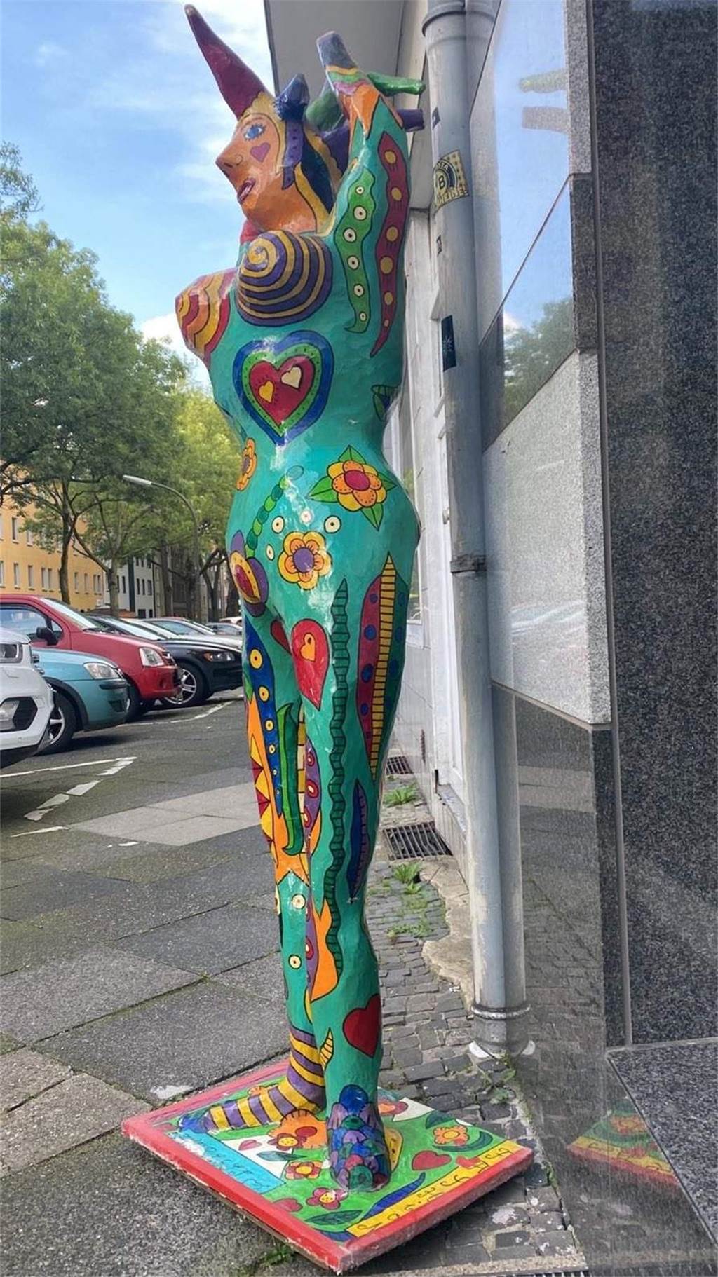 Die bunte Nana-Figur ist zu sehen wie sie bis Mittwoch vor dem Friseursalon von Adrienne Krane stand. Sie hat das typische Muster einer Nana und streckt die Arme in die Höhe.