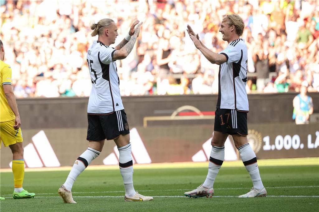 Marius Wolf und Julian Brandt klatschen miteinander ab.