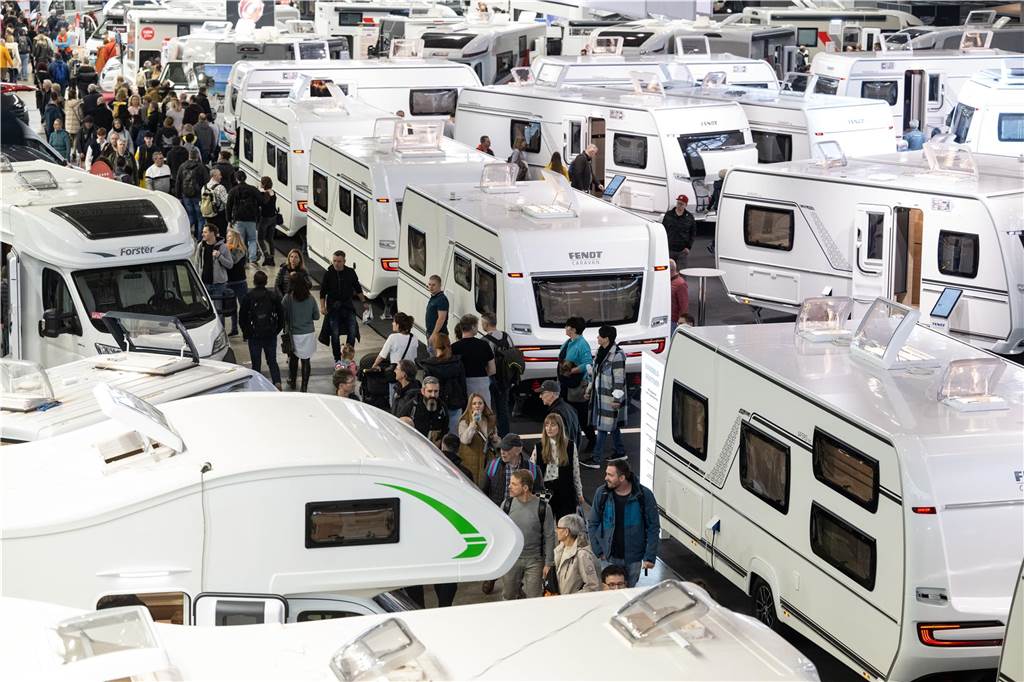 Camper gibt Tipps, was vor dem Kauf eines Wohnmobils zu bedenken ist Besucher strömen zwischen Wohnmobile auf einer Camping Messe.