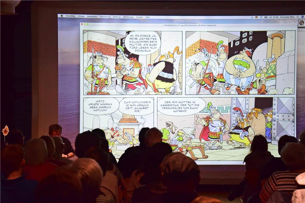 „Voll Panne, die Römers“: Autor Hennes Bender stellte neues Buch vor Die Comics waren hinter ihm an die Wand projiziert.