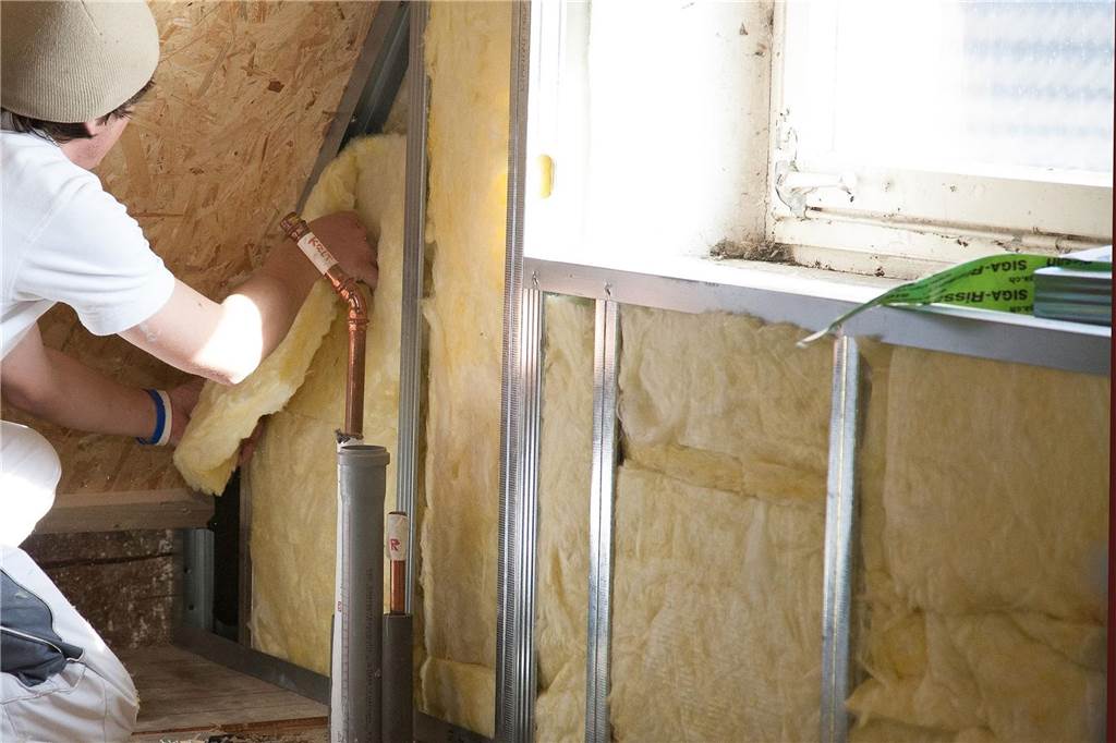 Wertverluste von Häusern in Werne: Ältere Häuser am stärksten betroffen Mann beim dämmen