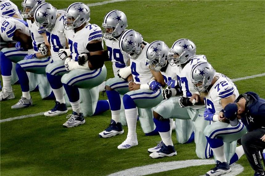 Die Dallas Cowboys knien auf dem Rasen nieder, bevor die US-Nationalhymne gespielt wird. Foto: Matt York