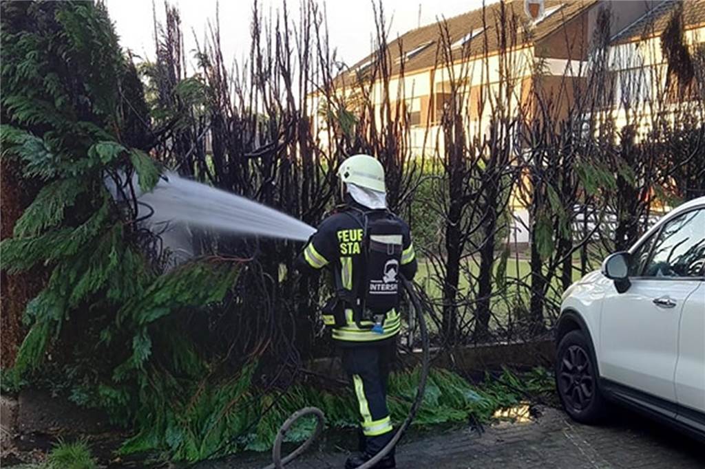 Feuerwehrmann löscht Hecke