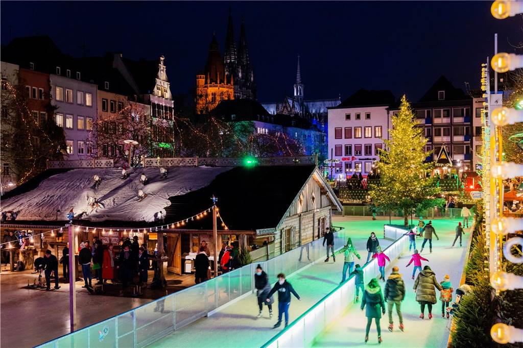 Weihnachtsmarkt Köln 2023: Öffnungszeiten, Highlights und Attraktionen Personen fahren Schlittschuh auf der Eisbahn auf dem Weihnachtsmarkt Heumarkt