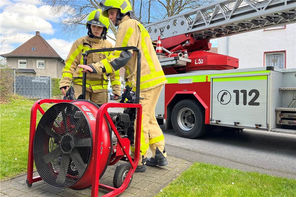 Die Feuerwehrleute nutzen einen Hochdrucklüfter, um den Rauch aus dem Flur und der betroffenen Wohnung zu bekommen.