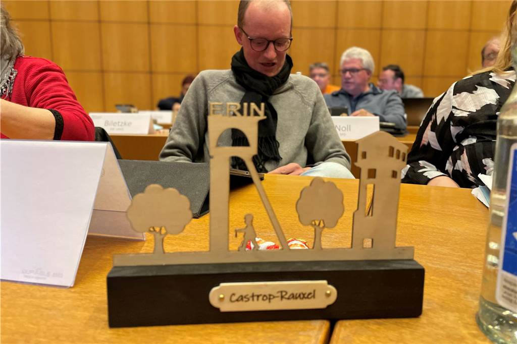 Eigenkapitalerhöhung für Stadtwerke: Was steckt hinter den 3,1 Millionen Euro? Die Fördertürme, zwei Bäume und der Bergmann: Diese Castrop-Rauxel-Skyline aus der Werkstatt des BBZ in Dingen bekam jedes Ratsmitglied, hier Malte Fercke (SPD) bei der letzten Ratssitzung 2023 geschenkt. Für Anette Korte (FWI) war der Mensch eher Kämmerer Michael Eckhardt auf der Suche nach den 40 Millionen Euro.