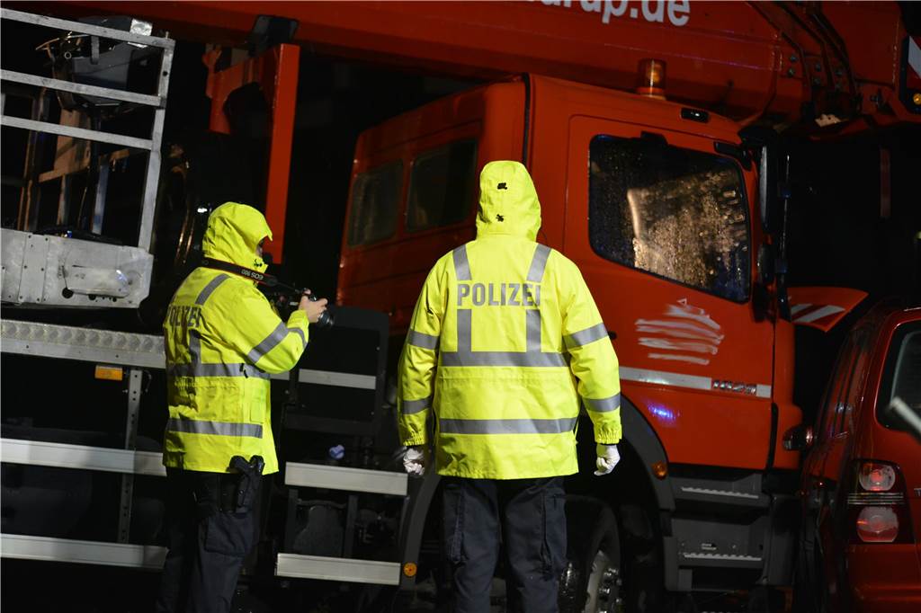 Zwei Polizeibeamte in gelben Regenjacken fotografieren in Waltrop einen verunfallten Lkw und einen verunfallten Pkw.
