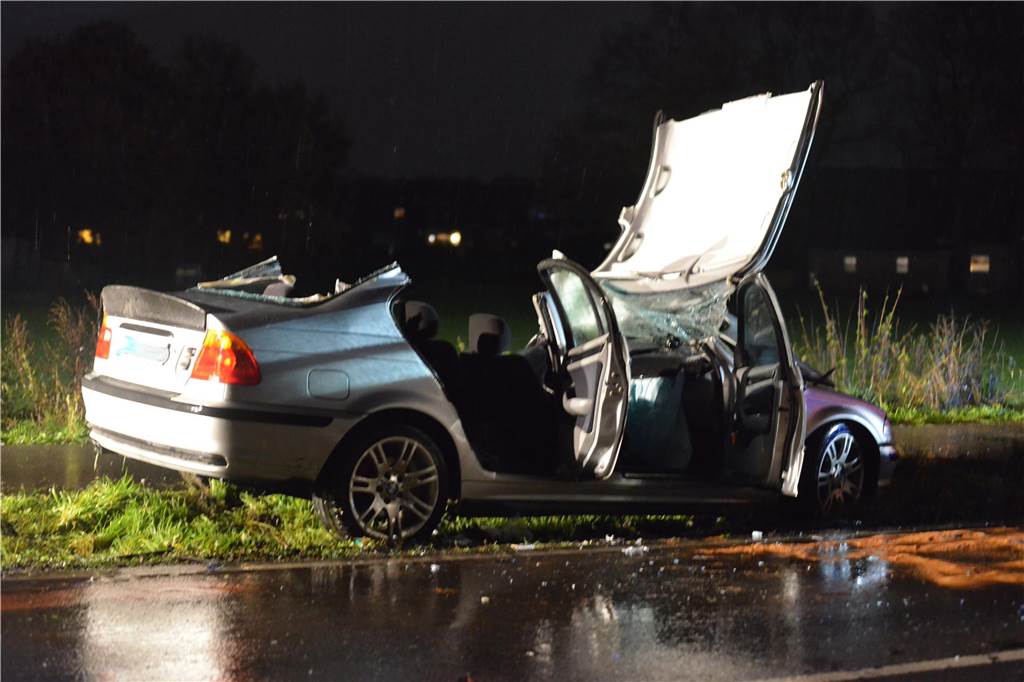 Ein bei einem Verkehrsunfall stark beschädigter silberner BMW steht in der Dunkelheit auf der Altenbruchstraße in Waltrop.