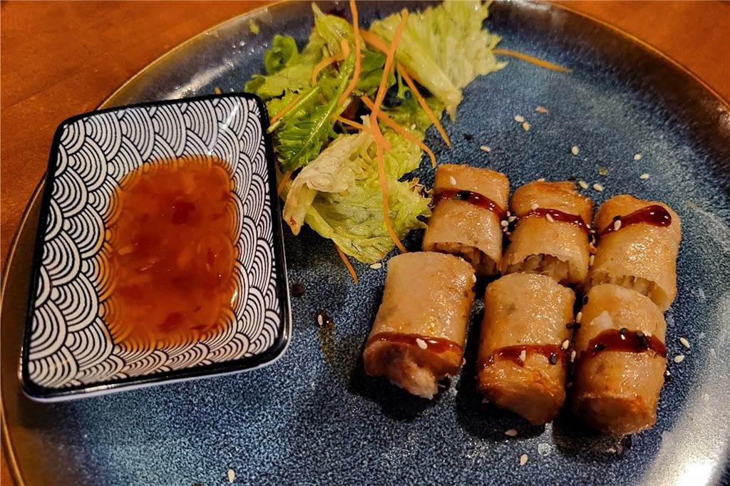 Kulinarische Reise nach Fernost Die Frühlingsrollen sind aussen knusprig und innen mit frischem Gemüse gefüllt. Dazu gibt es eine Salatbeilage und Süß-saure Soße.