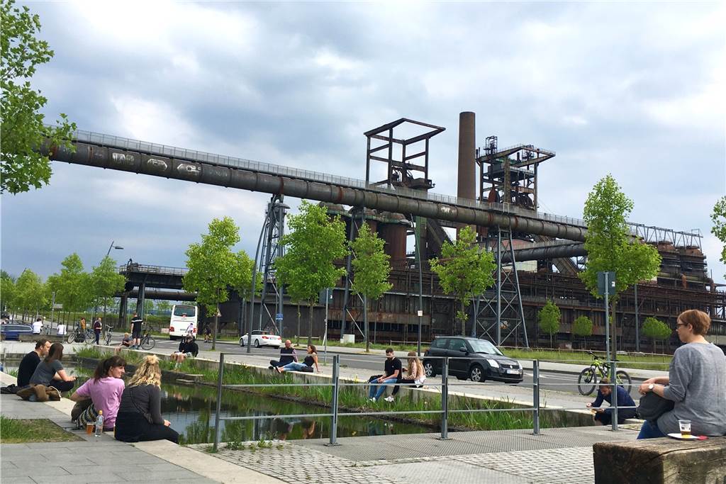 Stehbierhalle der Bergmann-Brauerei wappnet sich fürs lange Wochenende Die Menschen sitzen locker verteilt an den Wasserbecken vor dem alten Hochofen.