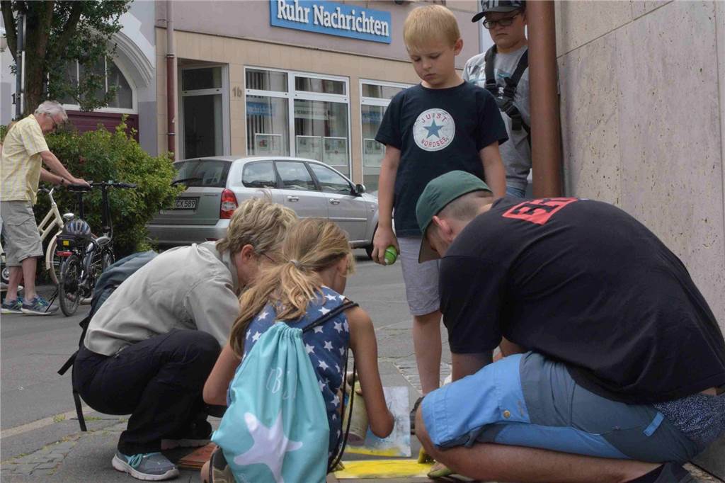 Warum viele gelbe Küken in die Schwerter Innenstadt gesprüht worden sind Die gelben Küken werden gemeinsam auf den Gehweg gesprüht.
