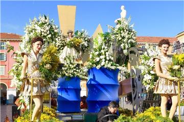 Die gelben Mimosen - hier unten am Fahrzeug und in den Armen der Frauen - finden sich an Karneval überall in Nizza. Foto: Christine Longin/dpa