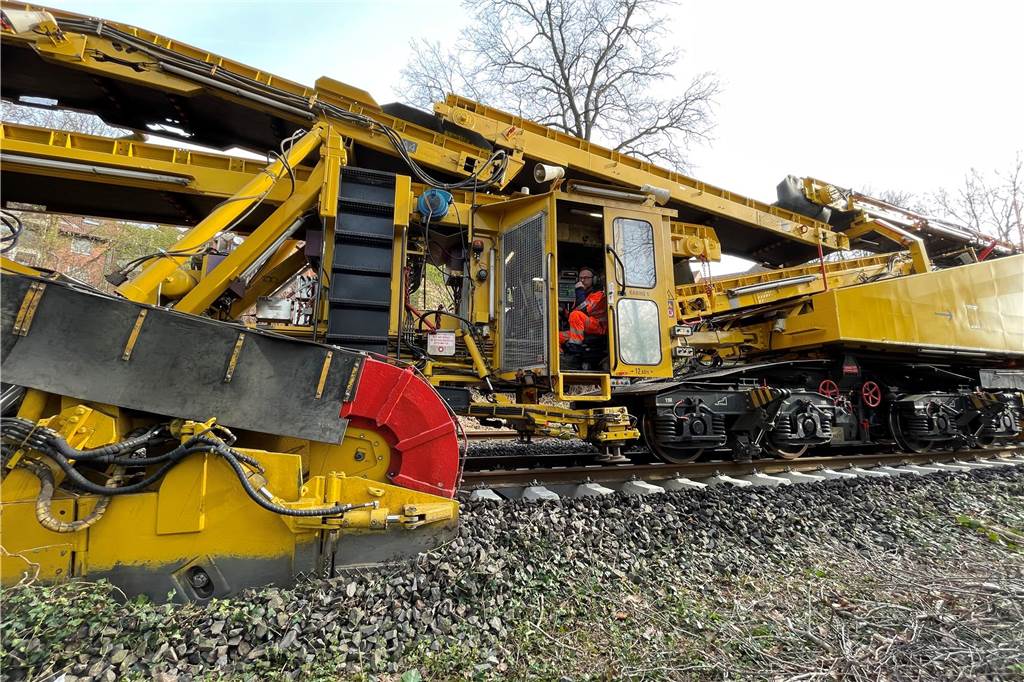 Mega-Maschine tauscht Bahnschwellen und reinigt Schotter im Sekundentakt Die Gleisbau-Maschine RUS 1000 S des österreichischen Bauunternehmens Swietelsky sammelt den Schotter ein, befördert ihn über Förderbänder über den Zug hinweg und verteilt den gereinigten Schotter dann wieder im Gleisbett.