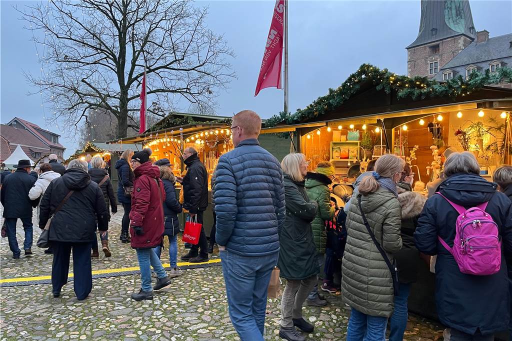 Menschen vor beleuchteten Ständen.