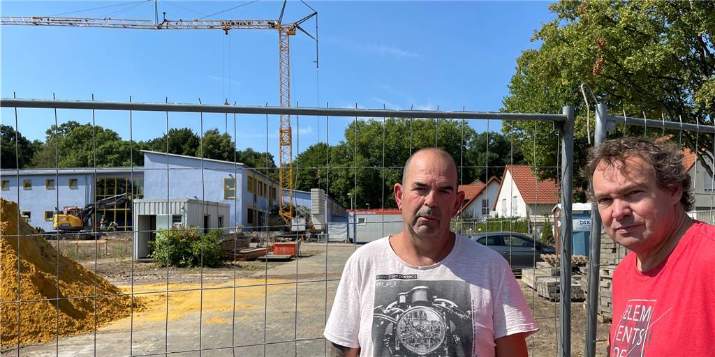 Kampf gegen Schul-Anbau in Dortmund geht weiter: „Immer noch total wütend“ Anwohner Ernst Kaaf (l.) und Matthias Sprenger am Baustellenzaun. Im Hintergrund die Hansa-Grundschule, die erweitert wird
