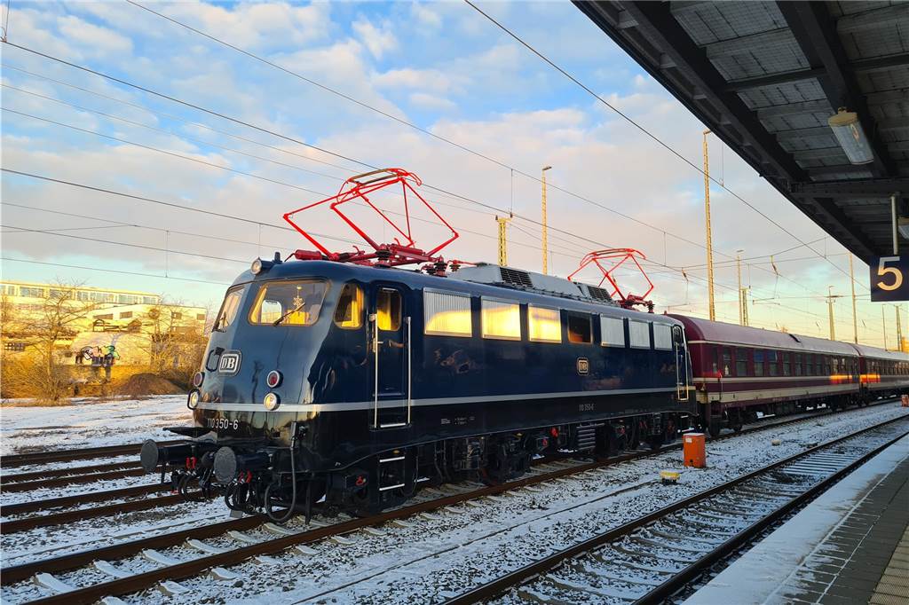 Ein Zug steht in einem Bahnhof. Die Schienen sind leicht eingeschneit.