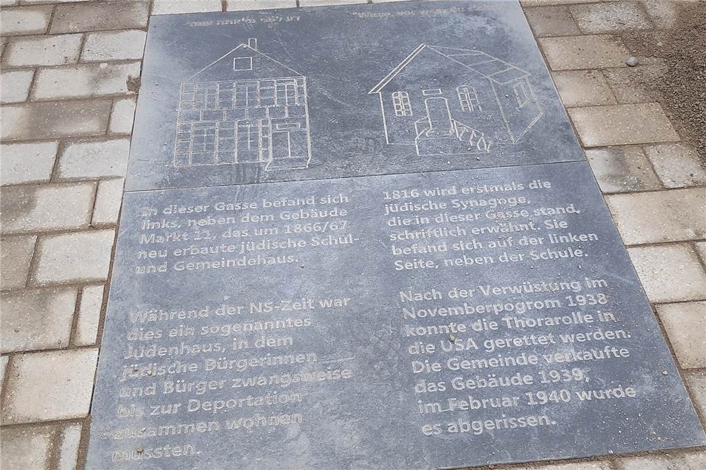 Im Video: Arbeiter verlegen neue Bodenplatte am Werner Marktplatz Die Inschrift enthält Informationen zur ehemaligen Synagoge und jüdischen Schule.