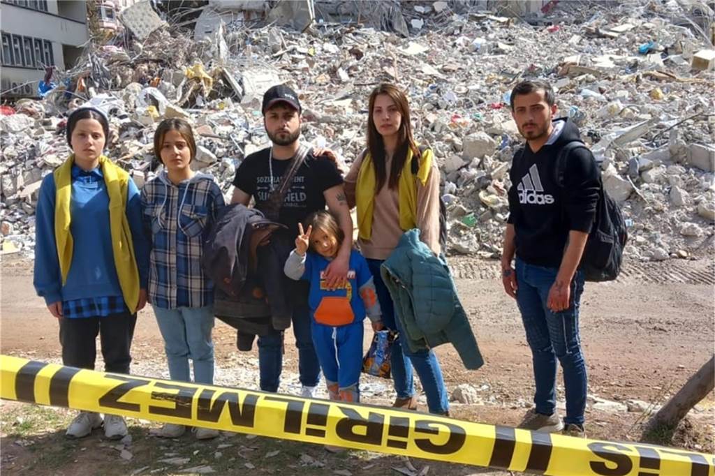 Die Kinder der Familie stehen vor dem völlig zerstörten Haus der Familie.
