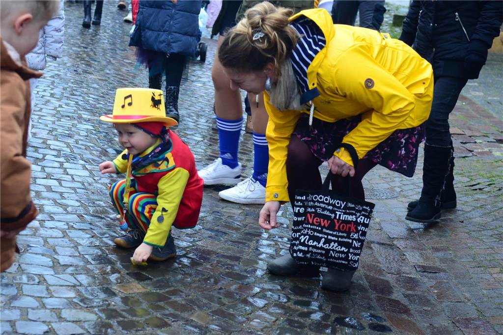 Ein kleiner Junge bückt sich und sammelt Kamelle auf.
