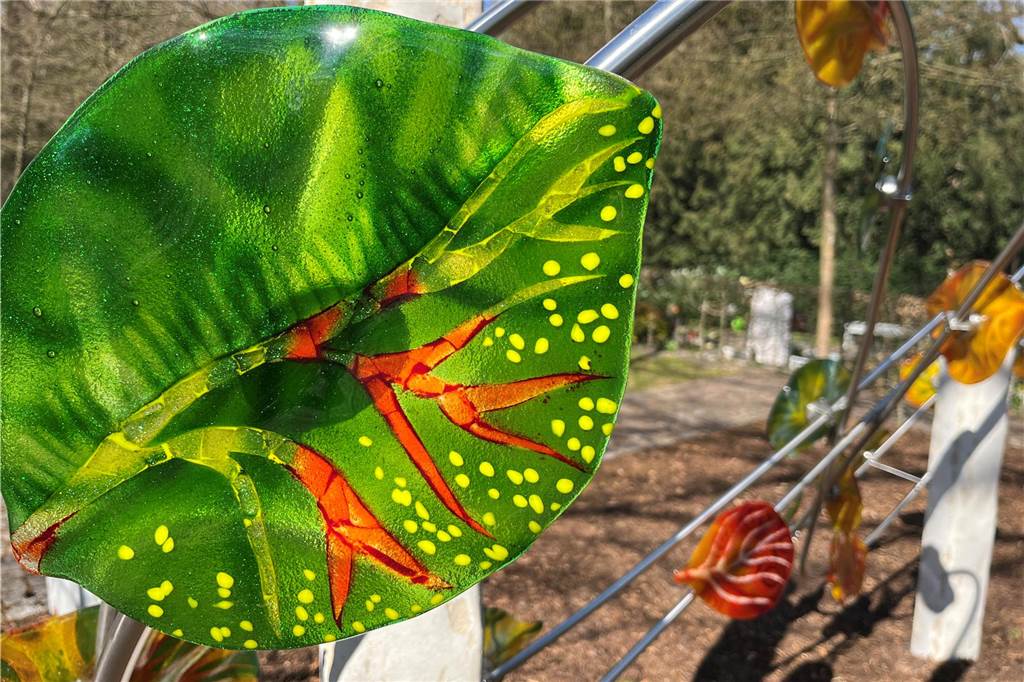 Kunst-Installation an Gedenkstätte als „Zeichen der unendlichen Liebe“ Ein leuchtend-grünes Glasblatt hängt an einem Edelstahlrohr auf dem Sundernfriedhof in Haltern an der Gedenkstätte für die Opfer des Germanwings-Absturzes.