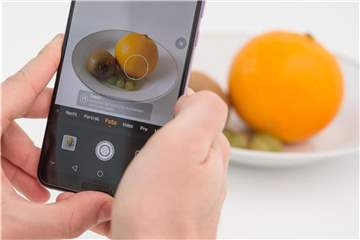 Die Künstliche Intelligenz in diesem Huawei Smartphone erkennt die Orange und richtet die Kamera für ein ansprechendes Food-Foto ein. Foto: Robert Günther/dpa-tmn